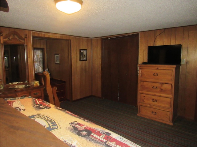 carpeted bedroom featuring wood walls and a textured ceiling