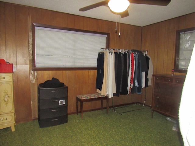 carpeted bedroom with wooden walls and a ceiling fan