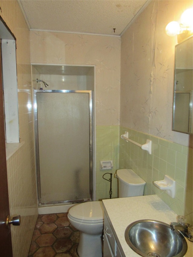 full bath with vanity, a shower stall, a textured ceiling, tile walls, and toilet