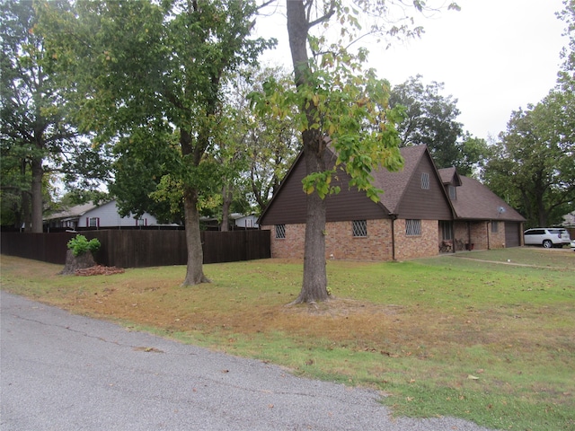 view of home's exterior featuring a yard, brick siding, and fence