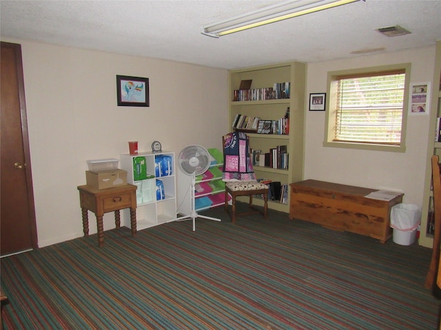 game room with dark carpet and a textured ceiling