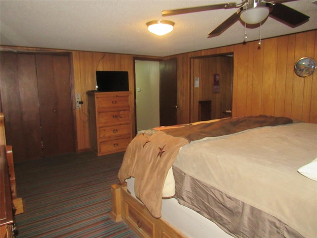 bedroom with ceiling fan, wood walls, and dark carpet