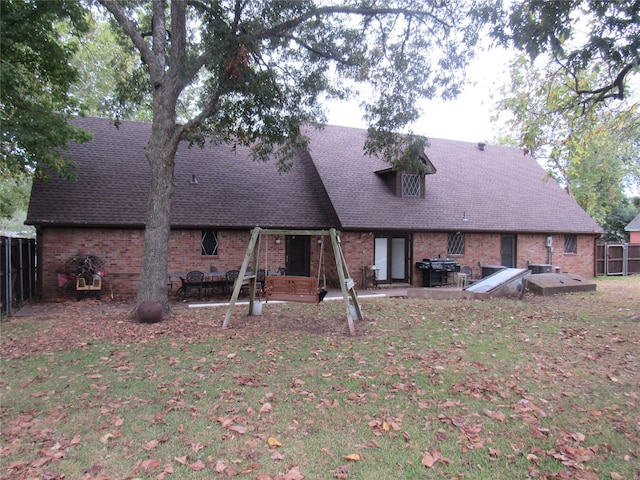 rear view of house featuring brick siding, a shingled roof, and a yard