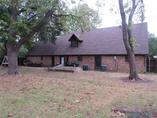 rear view of house with brick siding, central AC unit, and a shingled roof