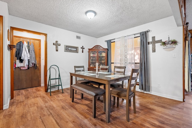 dining area featuring light hardwood / wood-style floors and a textured ceiling