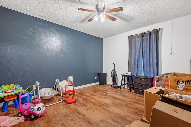 game room featuring ceiling fan, hardwood / wood-style floors, and a textured ceiling