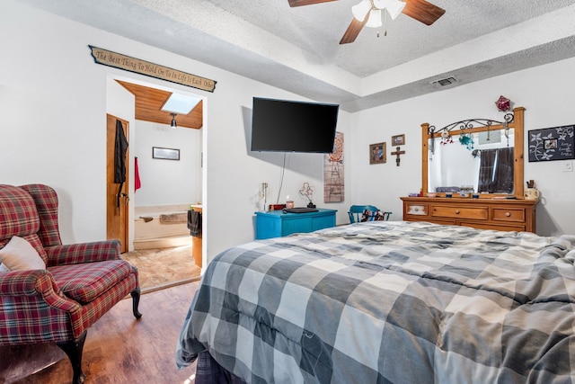 bedroom featuring hardwood / wood-style flooring, ceiling fan, a textured ceiling, and ensuite bath