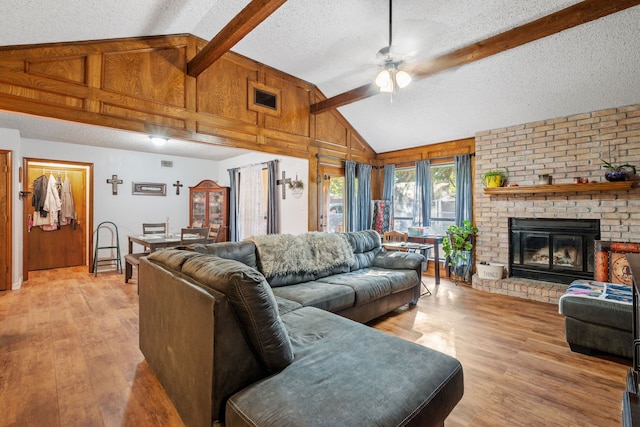 living room featuring lofted ceiling with beams, a textured ceiling, and light hardwood / wood-style flooring