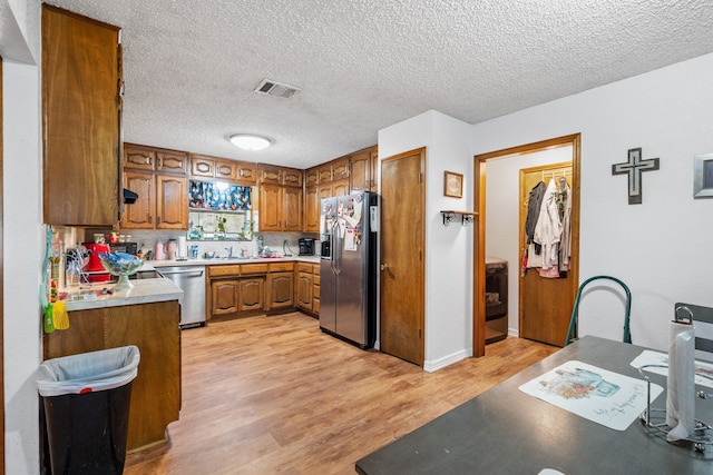 kitchen with sink, stainless steel appliances, light hardwood / wood-style flooring, a textured ceiling, and decorative backsplash