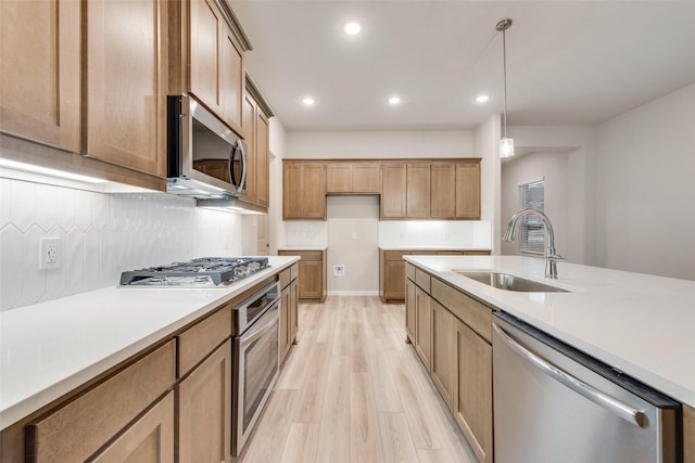 kitchen with sink, decorative light fixtures, light hardwood / wood-style flooring, stainless steel appliances, and decorative backsplash