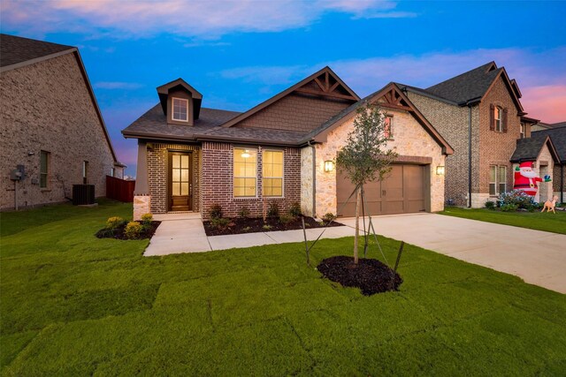 view of front of house featuring central air condition unit, a garage, and a lawn