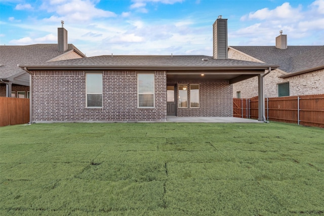 back of property with a yard and a patio area