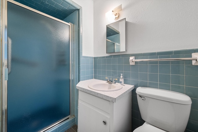 bathroom featuring vanity, tile walls, a shower with shower door, and toilet