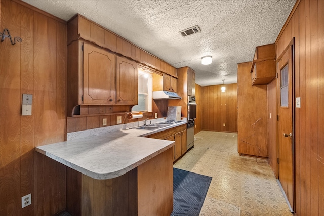 kitchen featuring wood walls, kitchen peninsula, and a textured ceiling