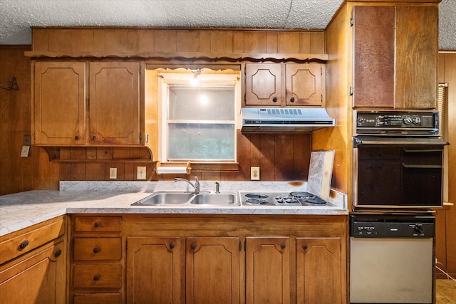 kitchen with a textured ceiling, stainless steel gas cooktop, black oven, and sink