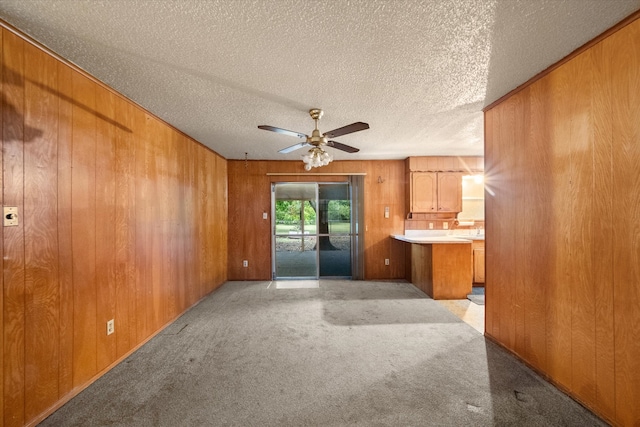 unfurnished living room with ceiling fan, light colored carpet, and a textured ceiling