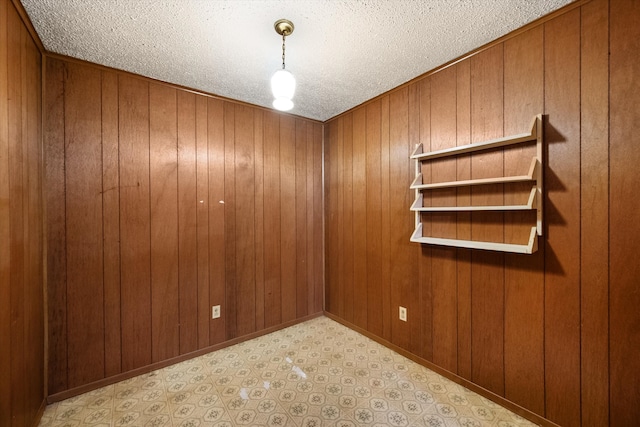 unfurnished room with wooden walls and a textured ceiling