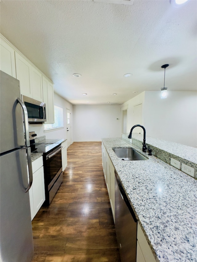 kitchen with pendant lighting, sink, stainless steel appliances, dark hardwood / wood-style floors, and light stone countertops