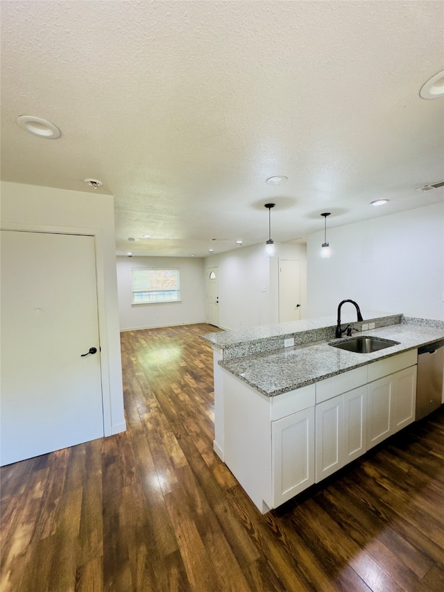 kitchen with white cabinetry, dark wood-type flooring, light stone countertops, pendant lighting, and sink