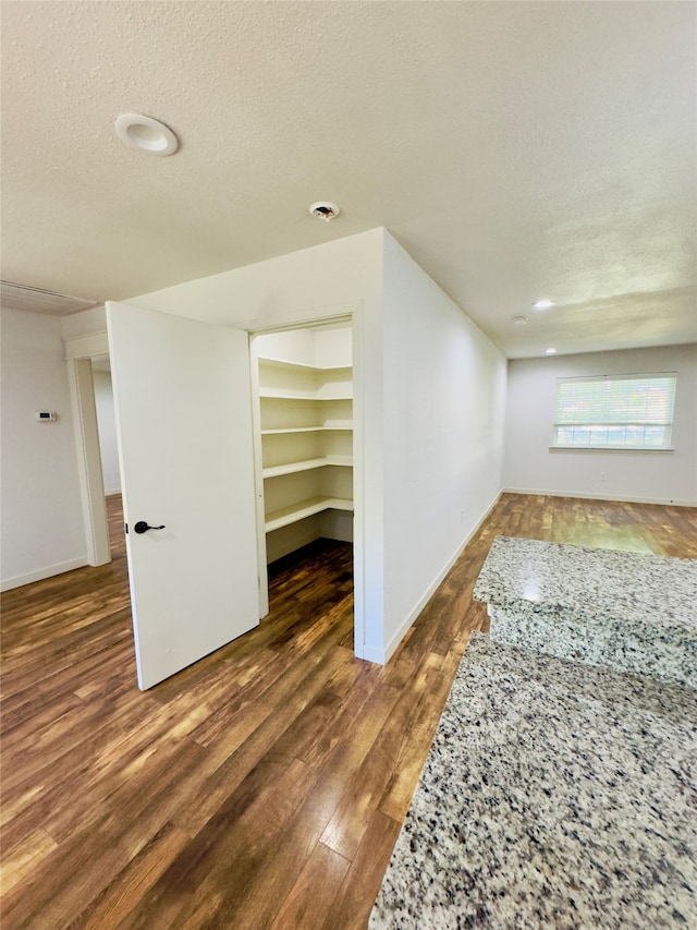 empty room with a textured ceiling and dark hardwood / wood-style floors