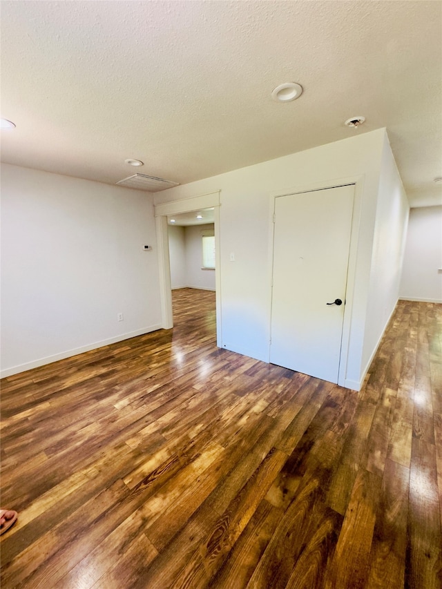 unfurnished bedroom featuring a closet, a textured ceiling, and dark wood-type flooring