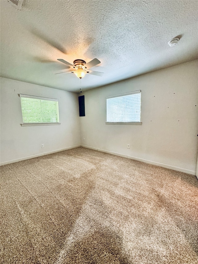 carpeted spare room featuring ceiling fan and a textured ceiling