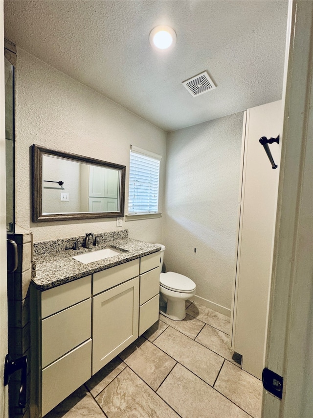 bathroom featuring vanity, toilet, a textured ceiling, and tile patterned floors