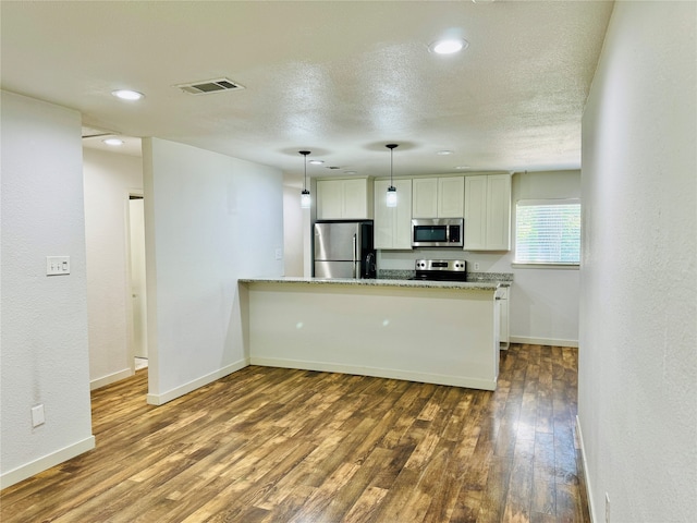 kitchen featuring light stone counters, white cabinets, kitchen peninsula, wood-type flooring, and stainless steel appliances