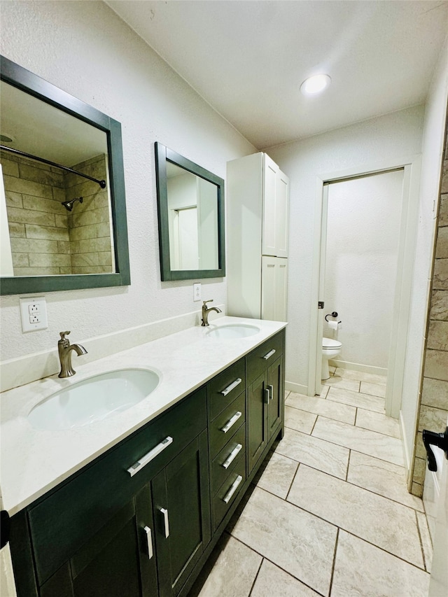 bathroom with a tile shower, vanity, tile patterned flooring, and toilet