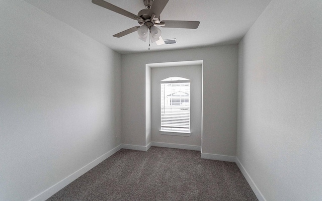 unfurnished room with visible vents, baseboards, dark colored carpet, and a ceiling fan