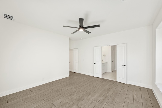 unfurnished bedroom featuring ceiling fan, light wood-type flooring, and connected bathroom