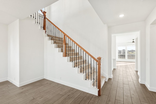 staircase featuring ceiling fan and hardwood / wood-style floors