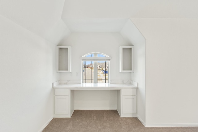 unfurnished office featuring light carpet and vaulted ceiling