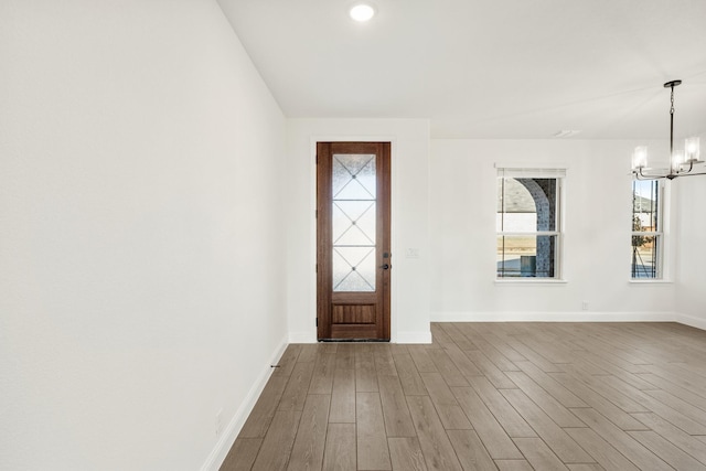 foyer entrance with hardwood / wood-style floors and a chandelier