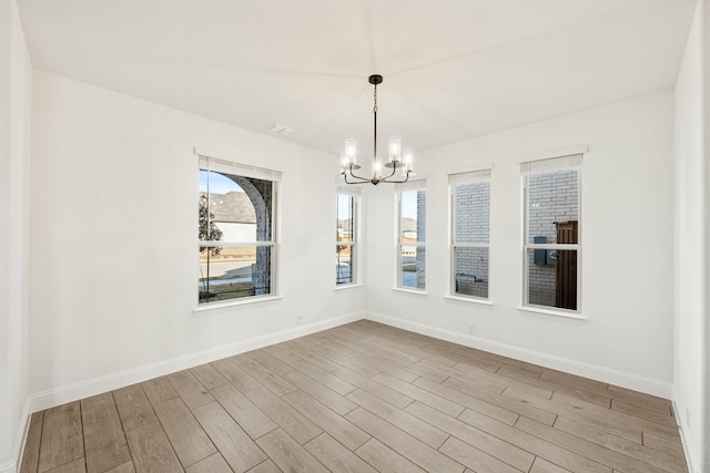 unfurnished dining area with light hardwood / wood-style floors and an inviting chandelier