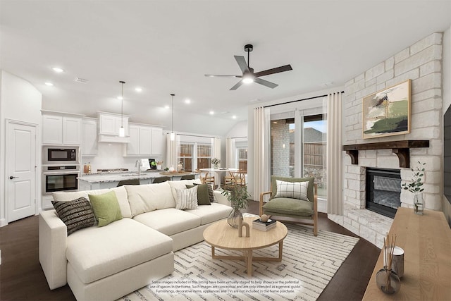 living room with sink, ceiling fan, a fireplace, light hardwood / wood-style floors, and vaulted ceiling