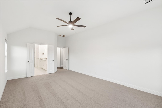 unfurnished bedroom featuring ceiling fan, ensuite bathroom, vaulted ceiling, and light carpet