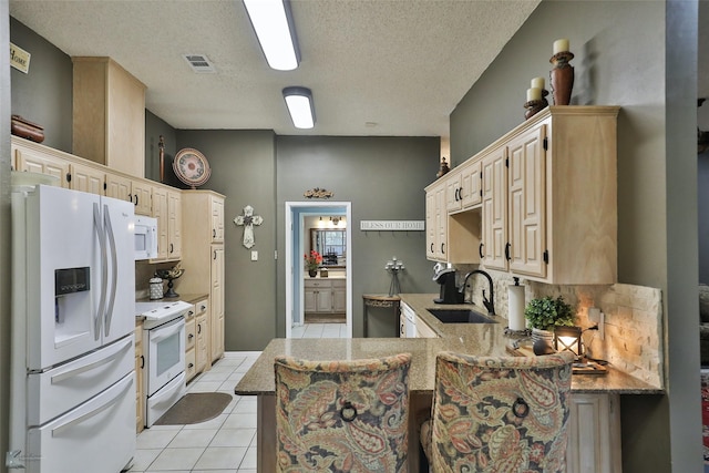 kitchen with white appliances, sink, light tile patterned floors, a textured ceiling, and kitchen peninsula