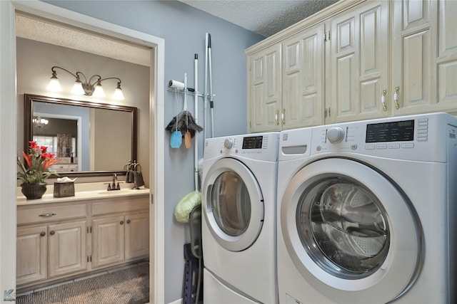 clothes washing area featuring sink, cabinets, a textured ceiling, and washing machine and clothes dryer