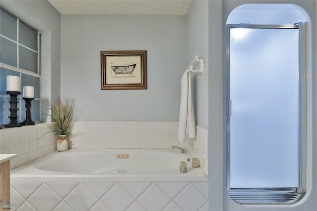 bathroom with tiled tub, vanity, and a textured ceiling