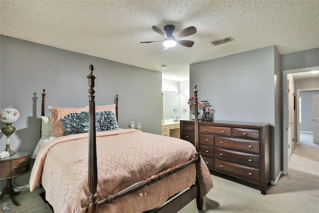 carpeted bedroom featuring a textured ceiling, ensuite bathroom, and ceiling fan