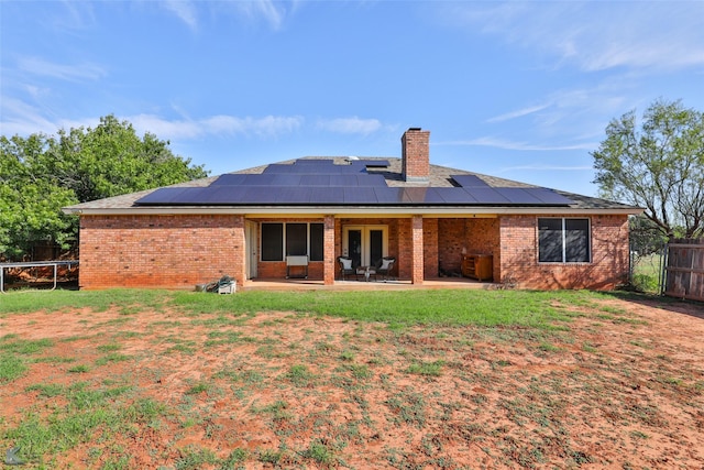 rear view of property with solar panels, a patio, a trampoline, and a lawn