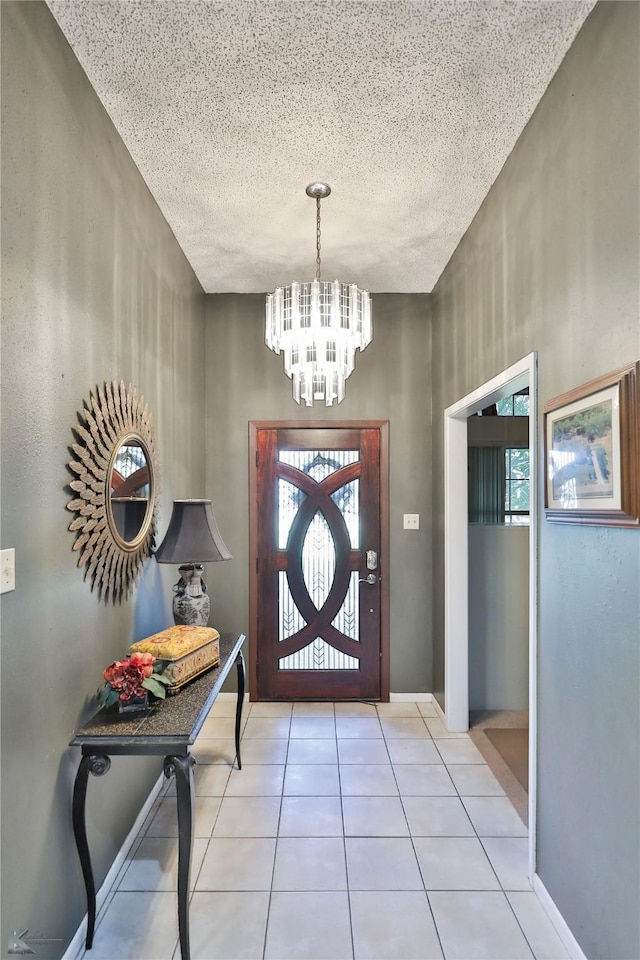 foyer entrance featuring a textured ceiling, an inviting chandelier, and light tile patterned flooring