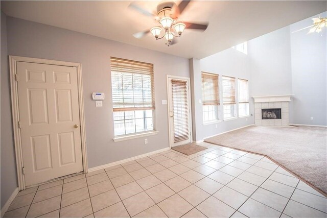 interior space with ceiling fan, light colored carpet, a fireplace, and plenty of natural light