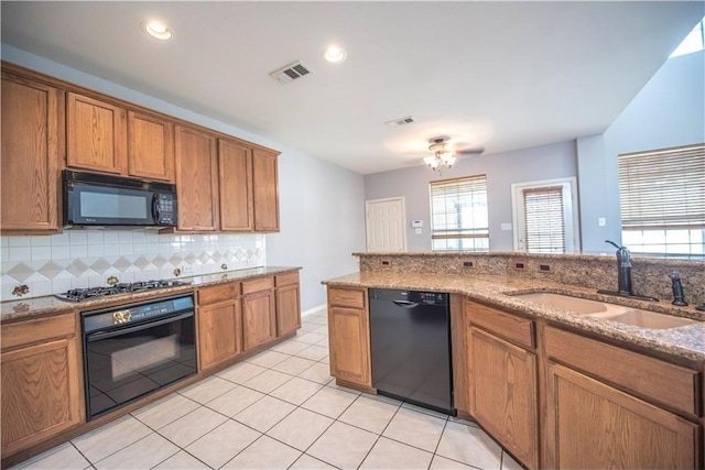 kitchen with black appliances, decorative backsplash, sink, and light stone countertops