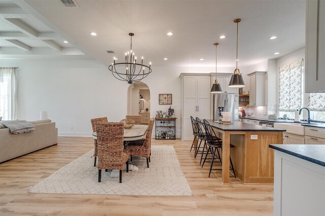 dining room with light wood-style floors, plenty of natural light, recessed lighting, and arched walkways