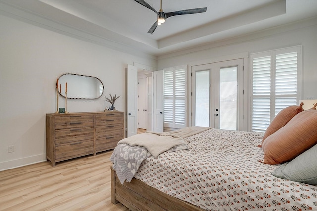 bedroom with access to outside, a tray ceiling, light wood-type flooring, a ceiling fan, and baseboards