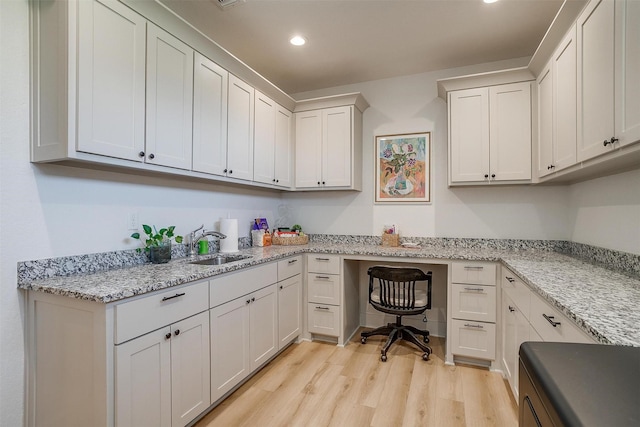 office space with recessed lighting, light wood-style flooring, built in study area, and a sink