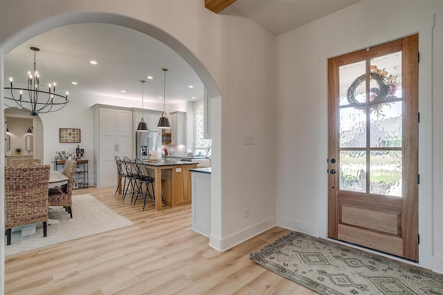entryway with recessed lighting, arched walkways, baseboards, light wood-type flooring, and a notable chandelier