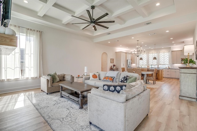 living area with light wood-style flooring, visible vents, arched walkways, recessed lighting, and ceiling fan with notable chandelier